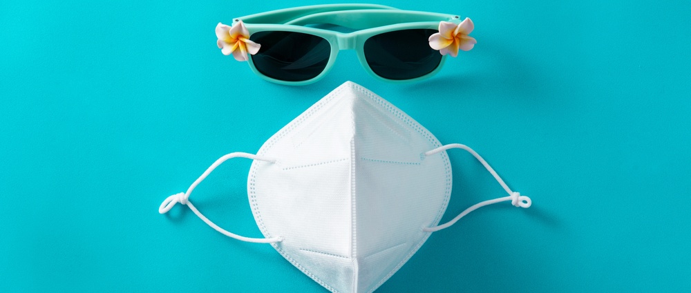 Sunglasses and protective face mask on blue background