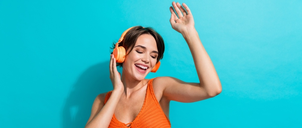 Photo of overjoyed lovely woman dressed knitwear singlet touching headphones hand up dancing listen music isolated on turquoise color background