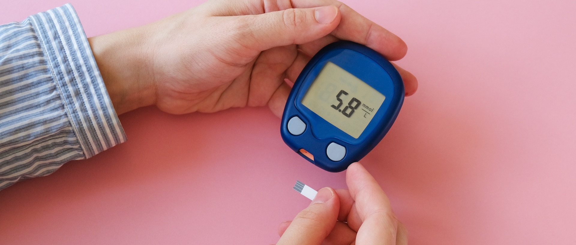 A close up of a pair of hands holding a glucometer.