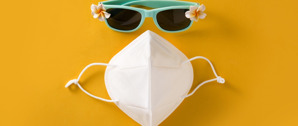 Sunglasses and protective face mask on yellow background