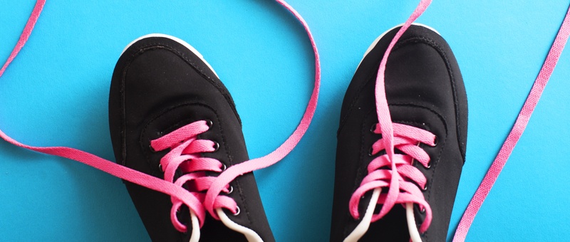 Black and pink running shoes against a blue background.