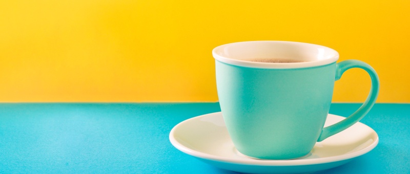 Cup of coffee with milk in a cup on colourful background