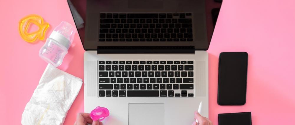Working mom top view flatlay of workplace baby items and laptop with phone