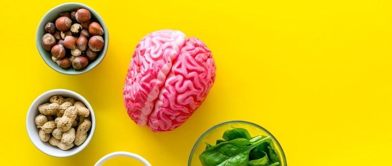 Brain food concept with peanut, hazelnut, seed-oil, spinach on yellow background top view.