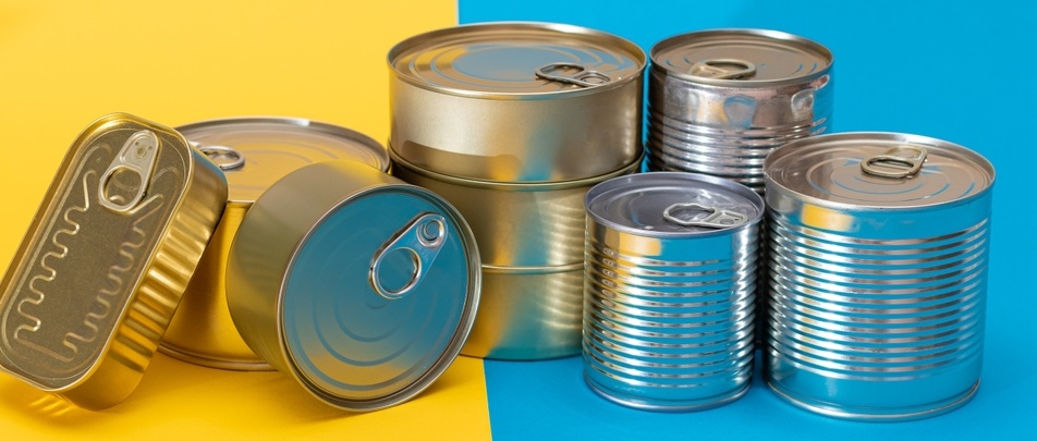 A Group of Stacked Tin Cans on Split Blue and Yellow Background. Canned Food. Aluminium Cans for Safe and Long Term Storage of Food. Steel Sealed Food Storage Containers