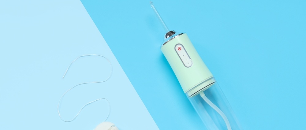 Oral irrigator and dental floss on color background