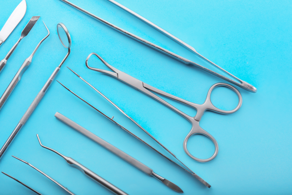 Silver surgical tools against bright blue background.