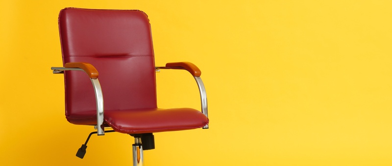 Red leather modern office chair on yellow background.