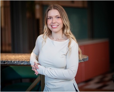 Bogomila Tosheva leaning against a high table and smiling at the camera