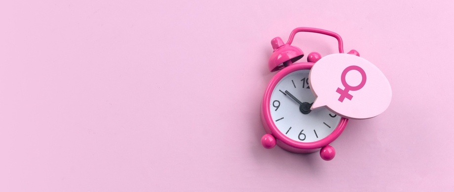 Menopause concept. Women symbol over a watch. Healthcare and medical for women. Pink background with copy space.