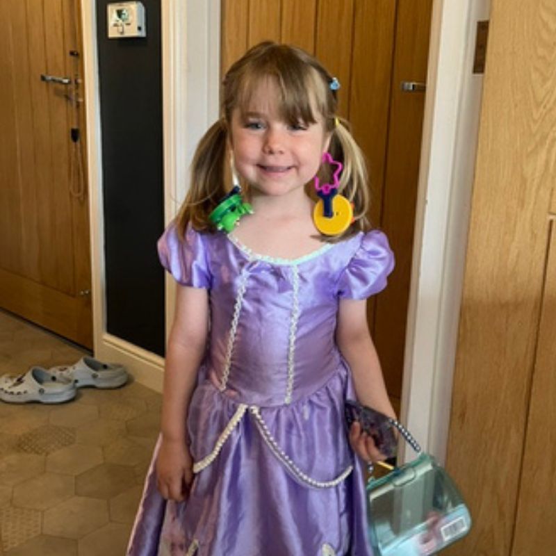 Little girl Ruby Marshall in a purple princess dress with brown-haired pigtails