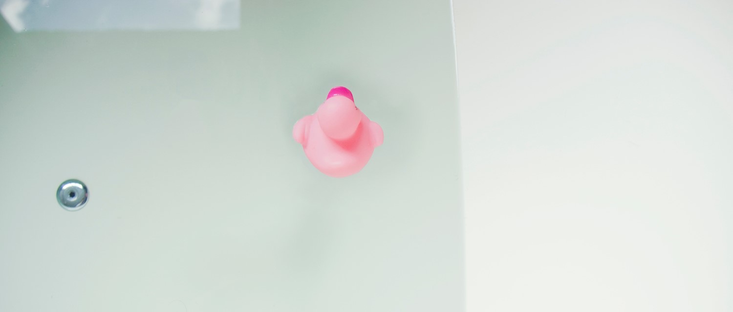 Photo of a pink rubber duck in a bathtub.