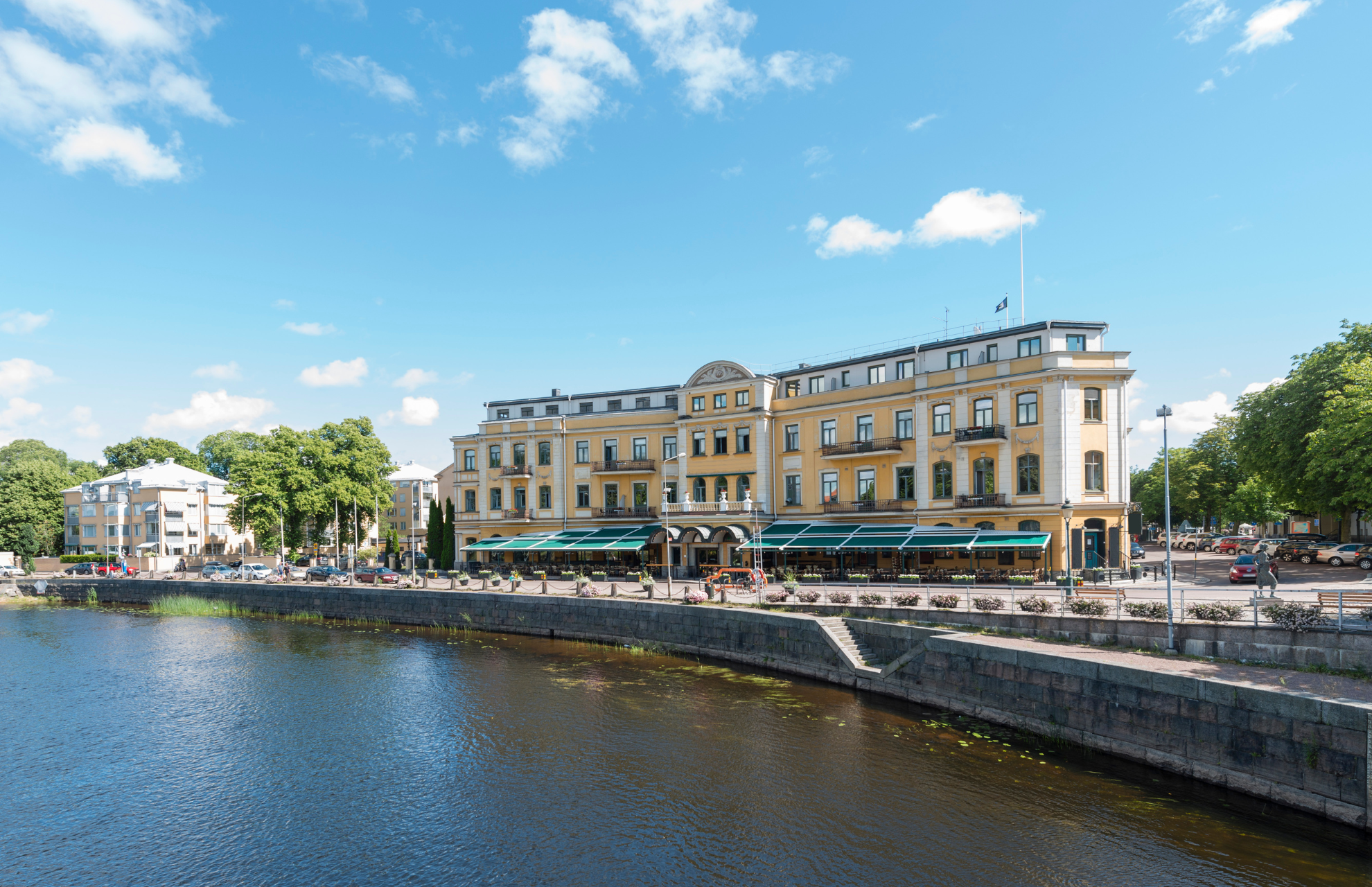 Gul fasad av Elite Stadshotellet i Karlstad med Klarälven framför
