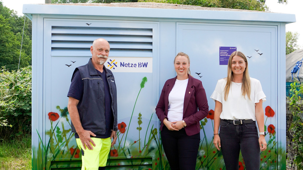 Stefan Vogel (Teamleiter Netzbetrieb der Netzregion Enz-Murg), Julia Wieland (Bürgermeisterin Remchingen), Any Schlatterer (Regionalmanagerin Netze BW)  stehen vor einer mit Graffiti neugestalten Trafostation.