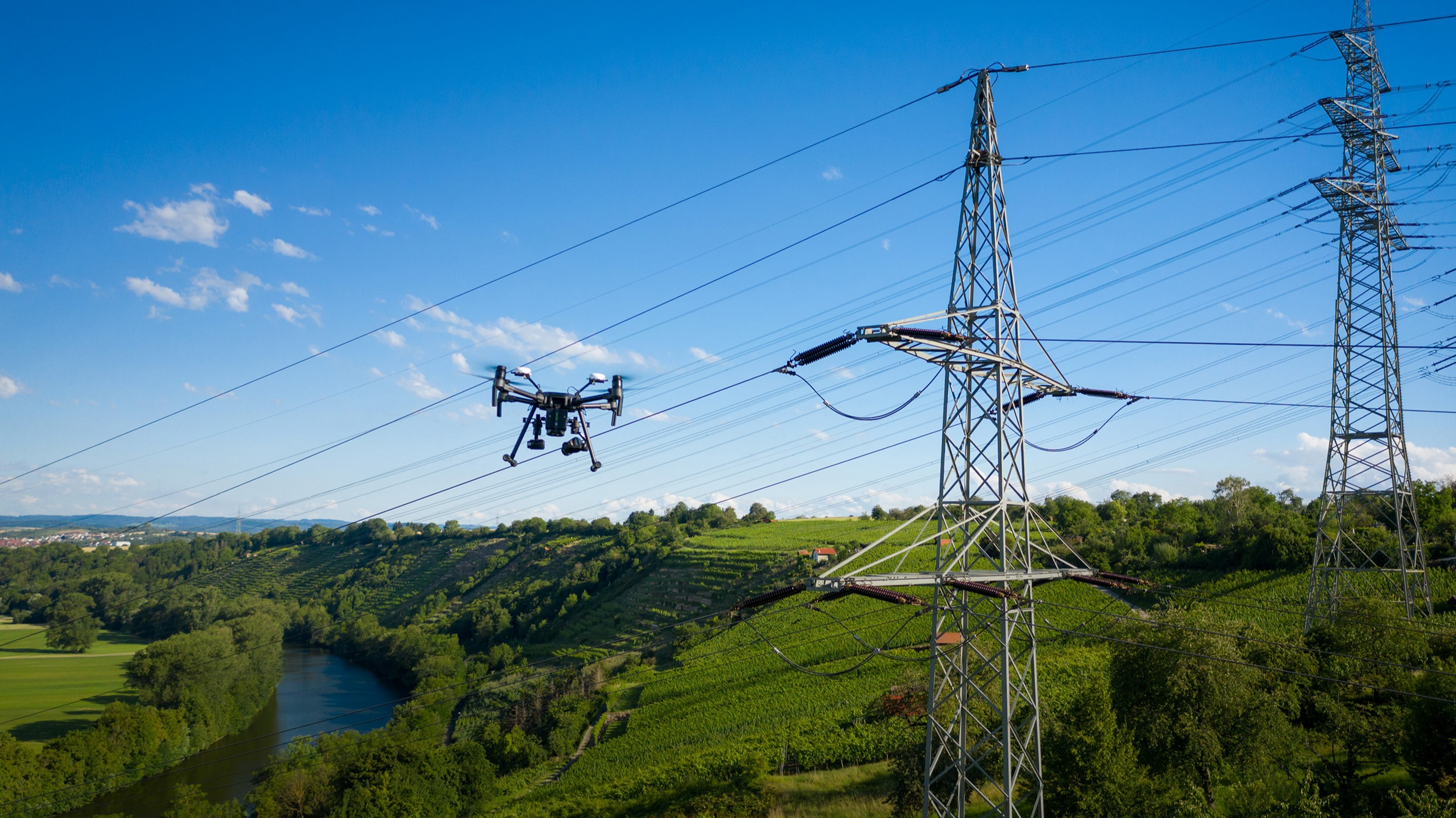 Drohne inspiziert Stromleitungen über Weinbergen.