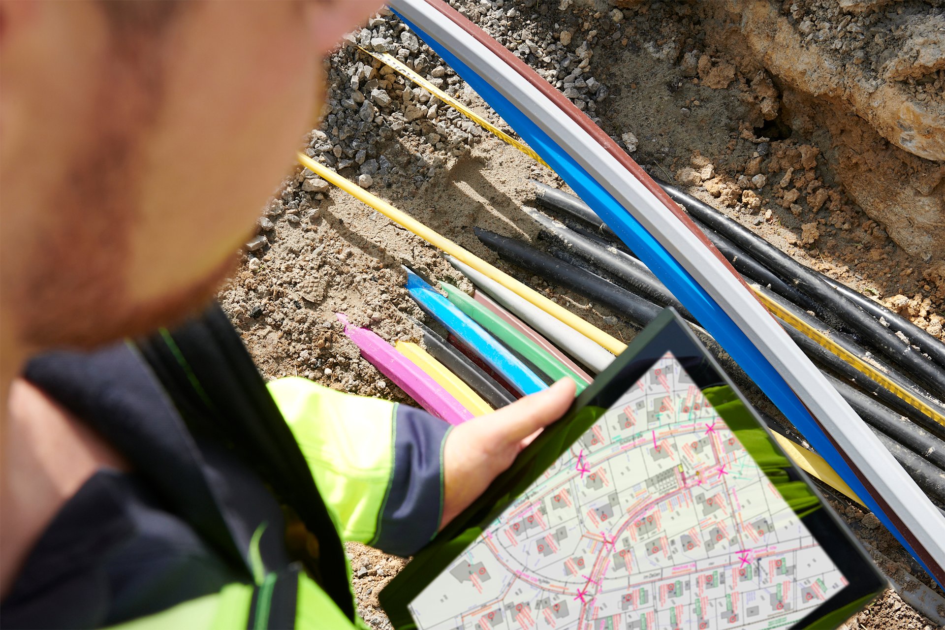 Techniker überprüft Kabelverlegung mit Plan auf Tablet.