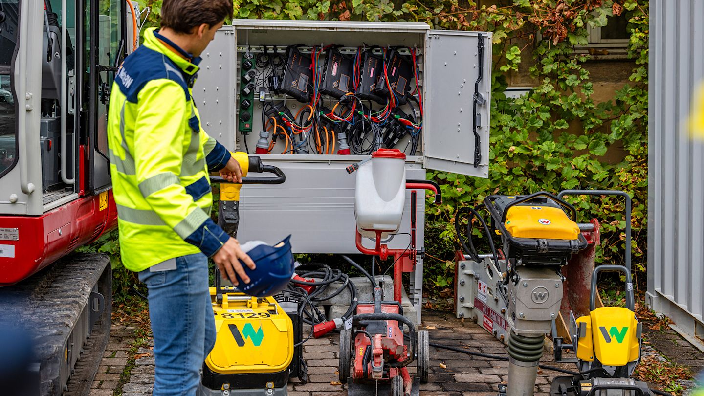 Elektrische Baustellenkleingeräte wie Rüttelblatte und Stampfer vor einem offenen Kabelverteilerschrank auf der Baustelle Bönnigheim