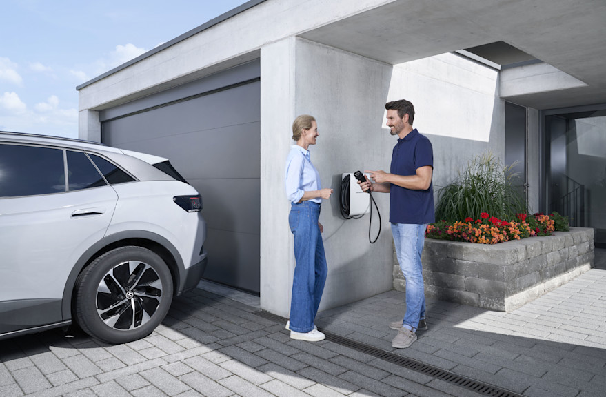 Elektroinstallateur berät Kundin neben ihrer Garage zur Wallbox.