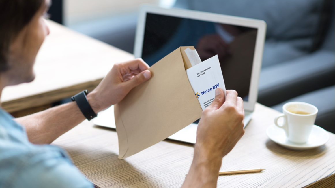 Mann öffnet Briefumschlag von Netze BW.