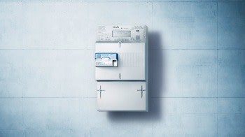 Ein einzelner moderner Smart Meter (elektronischer Stromzähler) ist mittig an einer Betonwand montiert.