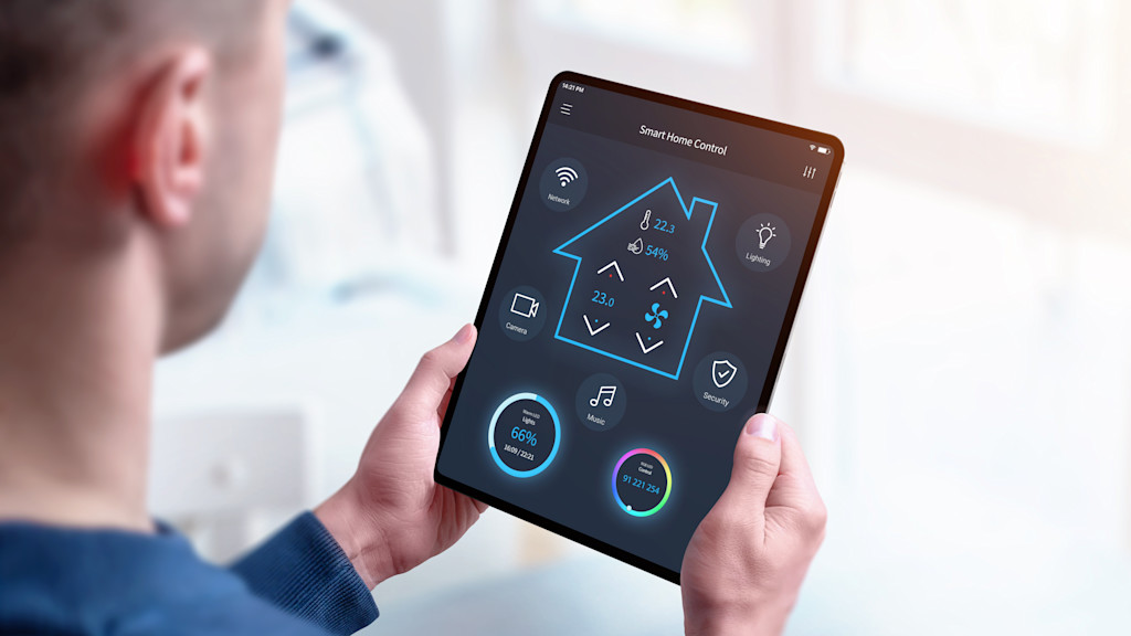 Mann steuert Smart Home via Tablet.