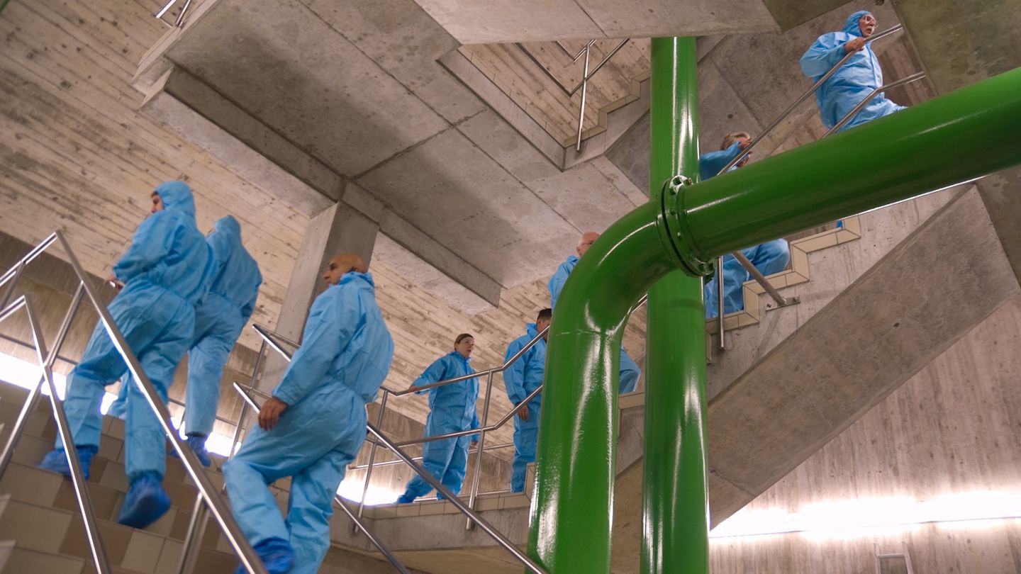 Menschen mit Schutzanzügen in einem Treppenhaus.