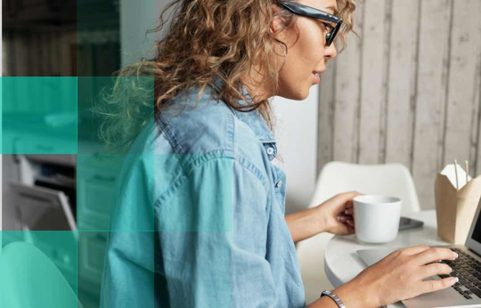 woman sitting at desk on laptop, drinking coffee. Decorative image