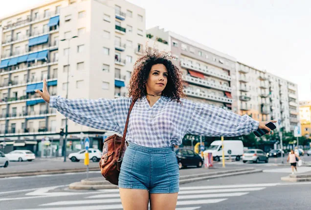 A woman in denim shorts crossing the street.