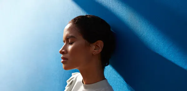 Girl soaking up the sun on a blue wall