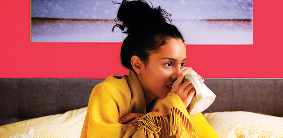 Girl covered with a blanket drinking hot drink