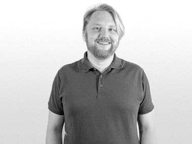 Mann guckt lächelnd frontal in die Kamera