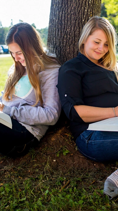 Two college students were studying under the shade of a tree.