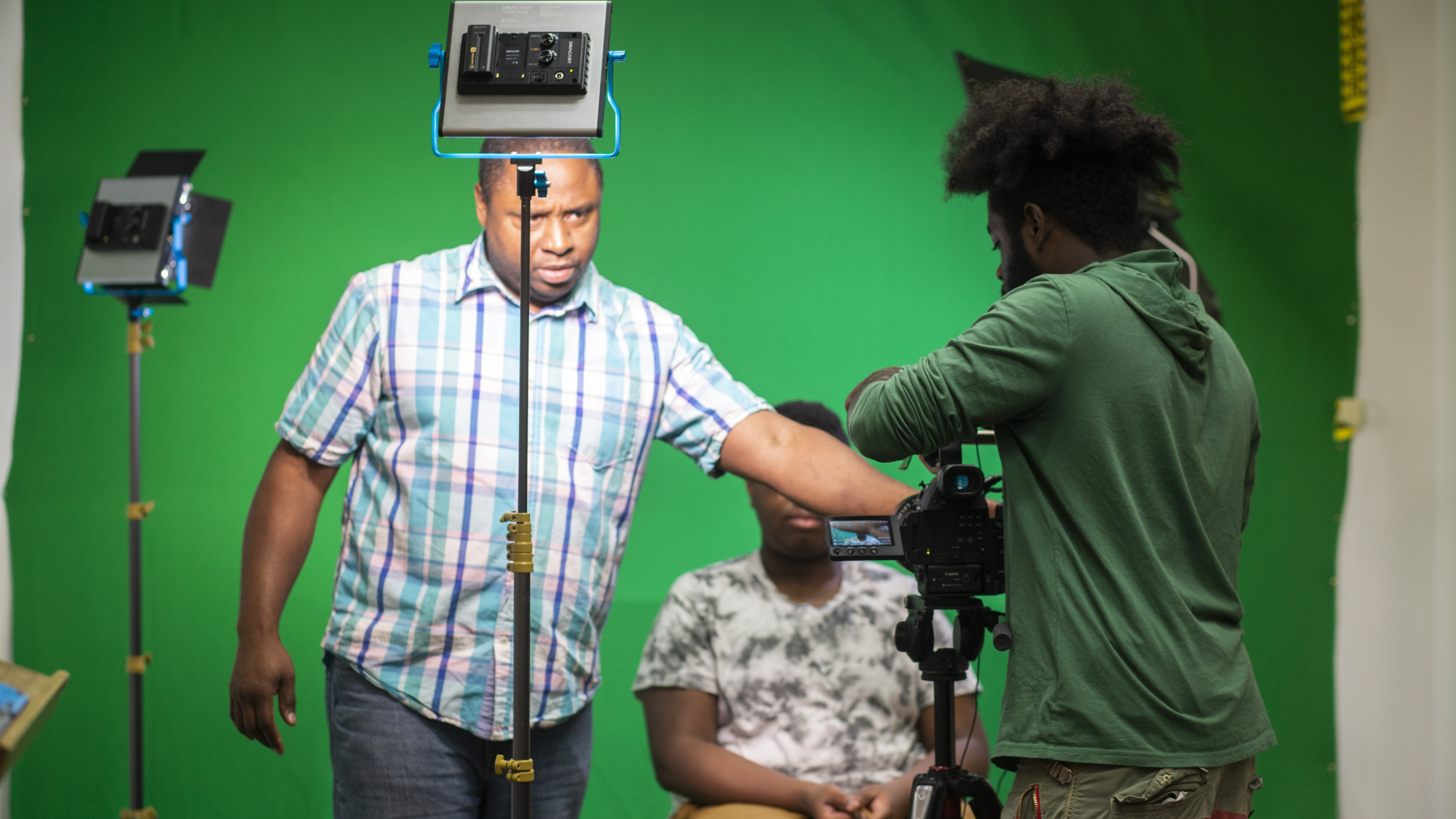 students filming in a studio setting with green screen