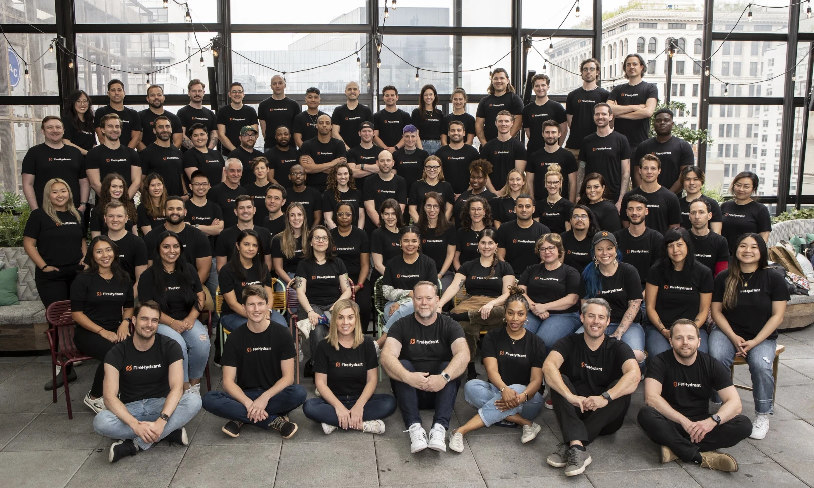 a formal portrait of the entire FireHydrant team standing in rows wearing black t-shirts with the FireHydrant logo on it