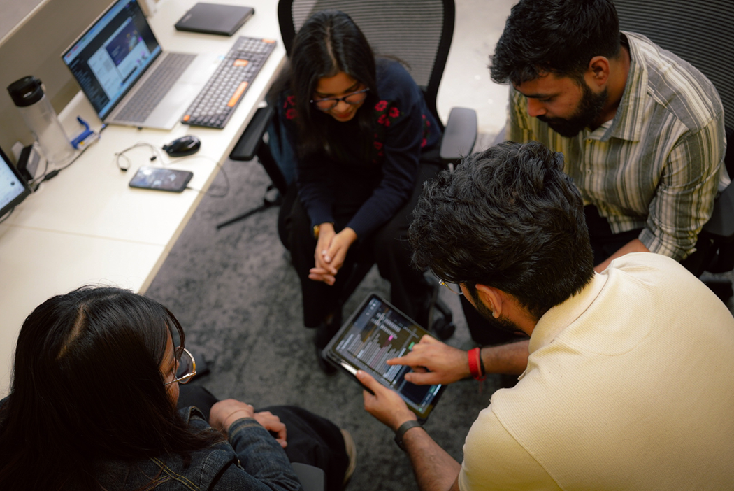 Digitup team collaborating over a tablet, highlighting their focus on innovation, R&D, and employee wellbeing