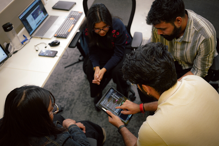 Digitup team collaborating over a tablet, highlighting their focus on innovation, R&D, and employee wellbeing