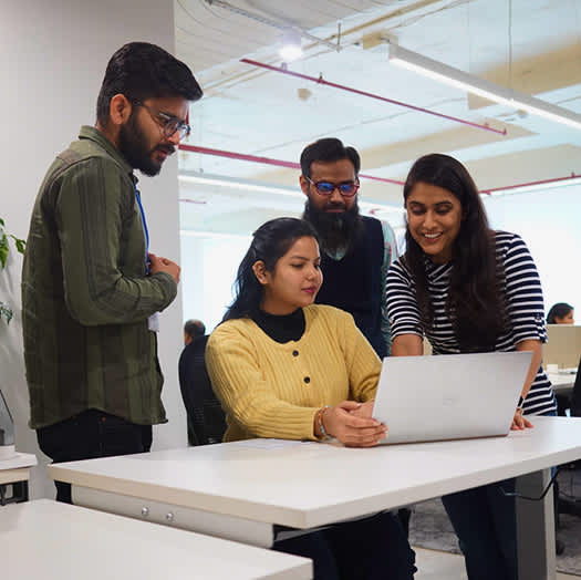 Digitup team collaborating around a laptop, reflecting their commitment to core values like trust, transparency, and collaboration