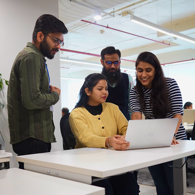 Digitup team collaborating around a laptop, reflecting their commitment to core values like trust, transparency, and collaboration
