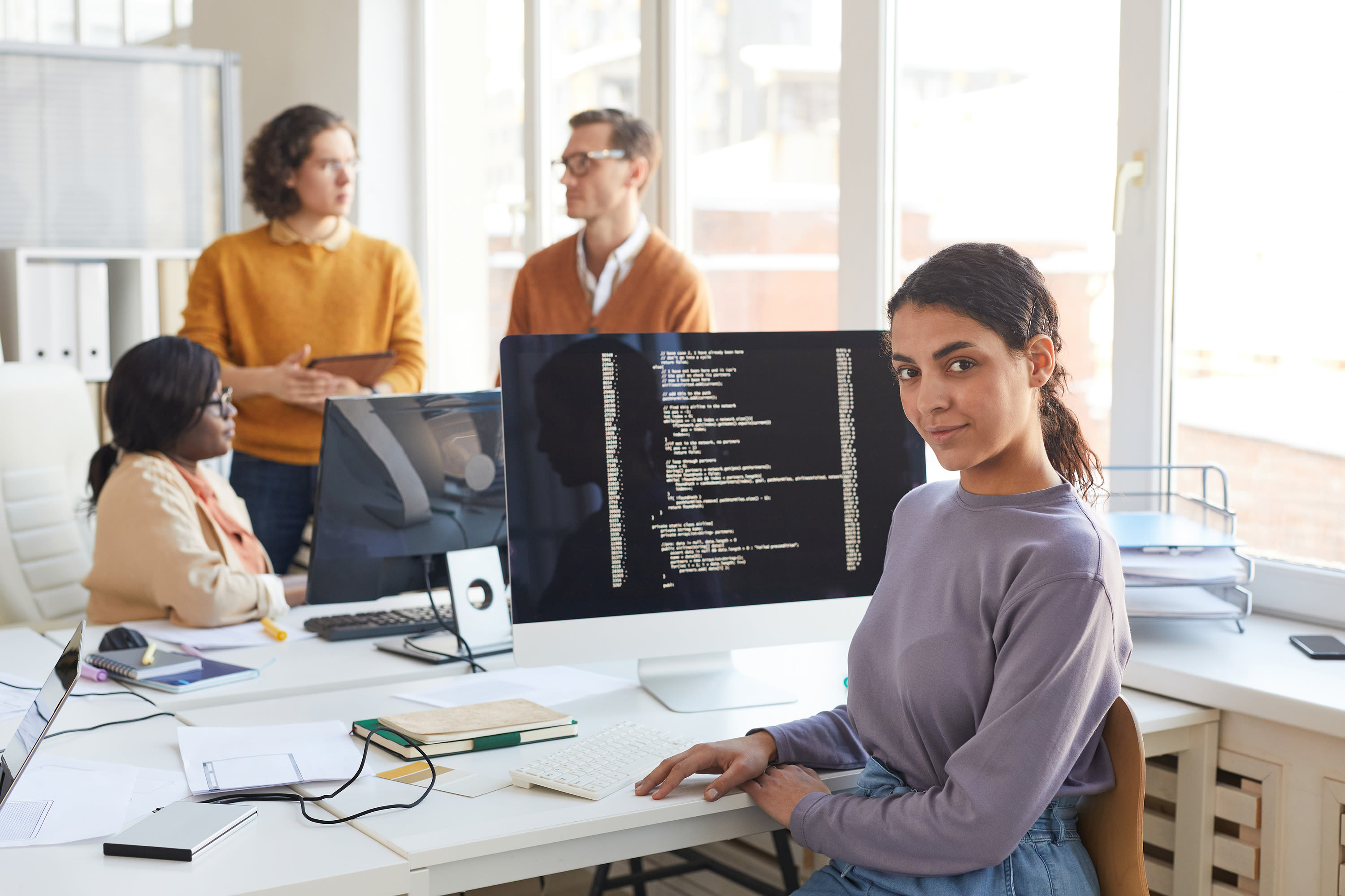 portrait-female-it-developer-looking-camera-while-posing-against-computer-with-code-screen-software-production-studio-copy-space2