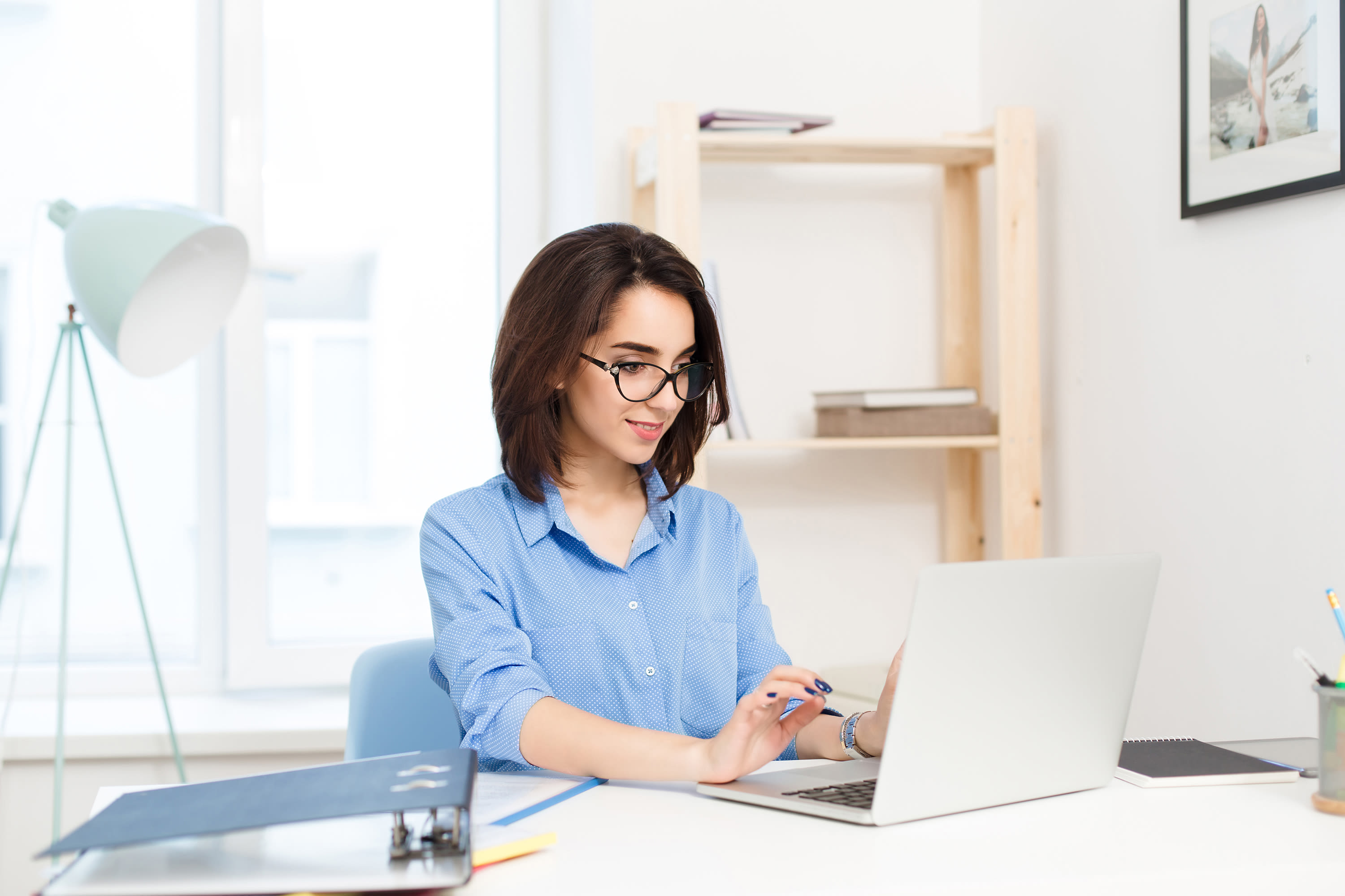 pretty-brunette-girl-blue-shirt-sitting-table-office-she-is-typing-laptop-looks-happy2