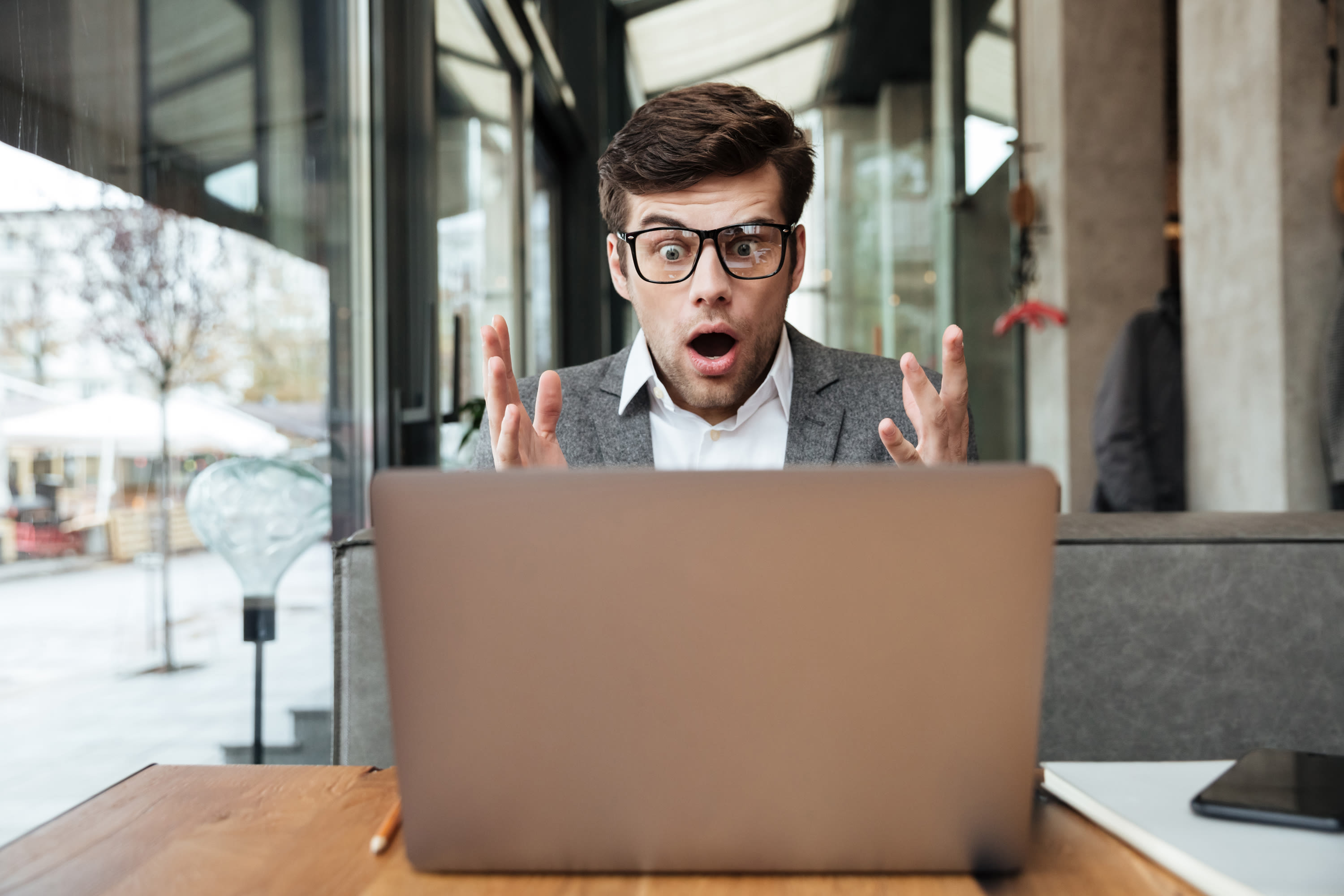 shocked-businessman-eyeglasses-sitting-by-table-cafe-looking-laptop-computer2