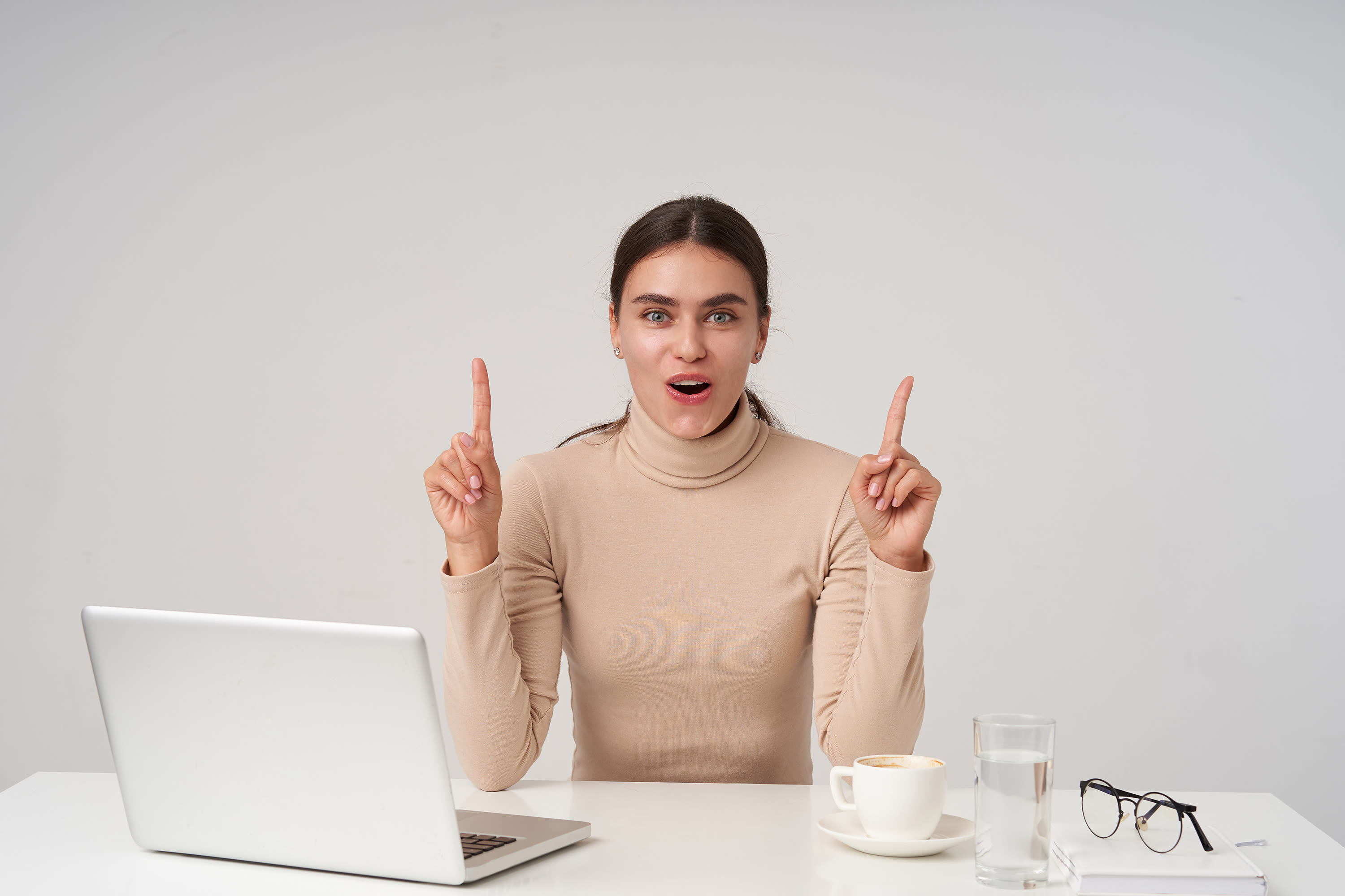 emotional-young-pretty-dark-haired-woman-with-ponytail-hairstyle-raising-hands-as-she-is-having-idea-looking-with-excited-face-posing-white-wall2