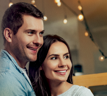 Una pareja joven se encuentra sonriente revisando todos los beneficios a los que pueden acceder por tener las Cesantías en Protección