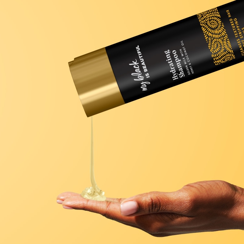 Golden Milk Hydrating Shampoo pouring onto the palm of a hand
