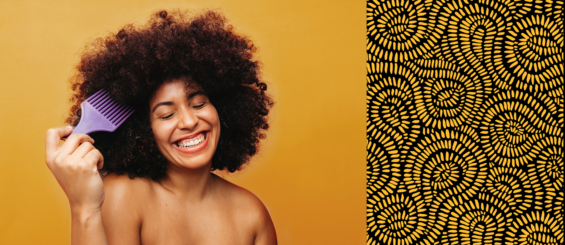 African American girl with an afro standing in front of a yellow background smiling as her head is tilted 