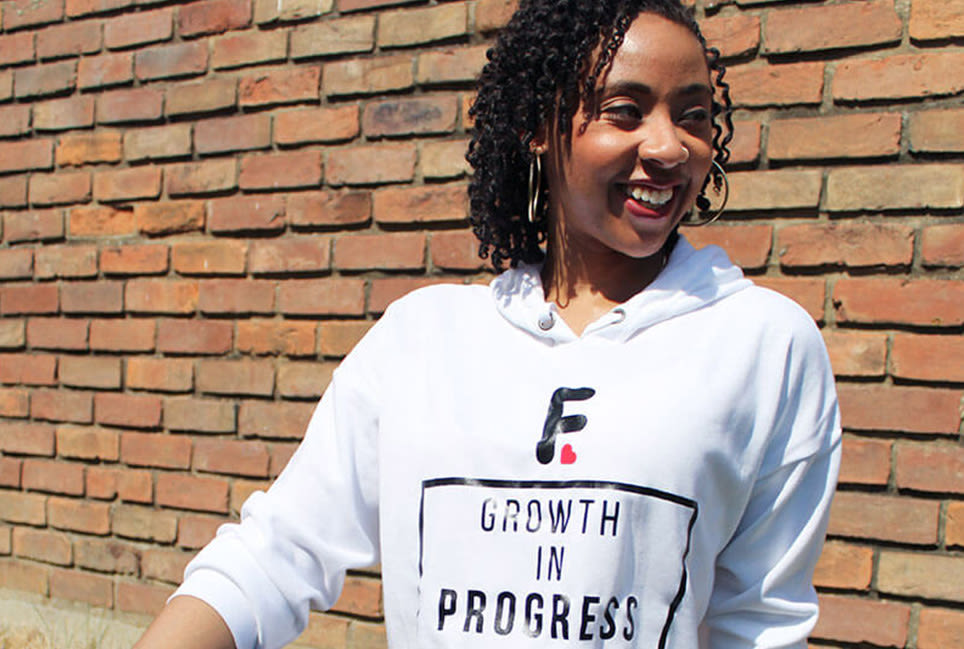 Black woman in T-shirt next to a brick wall