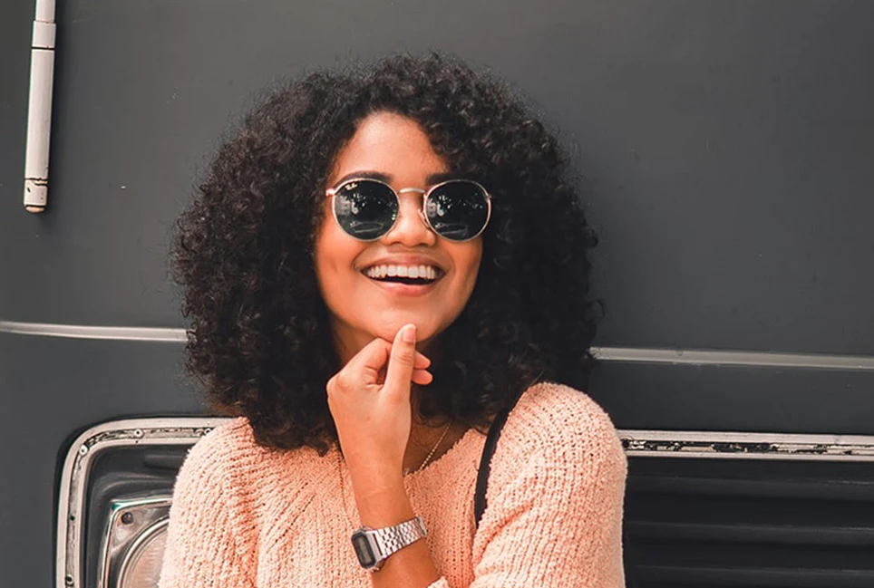 Woman smiling with curly hair and sunglasses