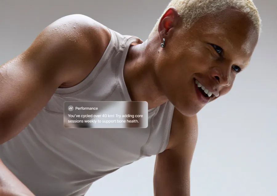 A man riding a Bike+ Pro with an overlay on top saying, "Performance: You've cyclced over 40km! Try adding core sessions weekly to support bone health."