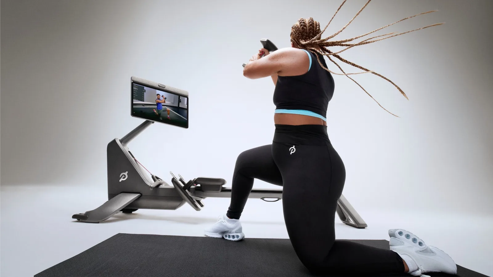 A woman exercising next to a Peloton Row+ Pro rower