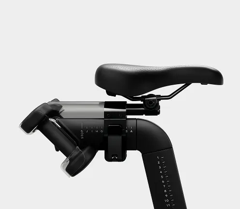 Close-up of the Peloton Bike+ saddle with rear dumbbell holders and adjustment markings on the seat post